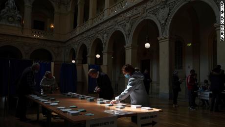 Женщина выбирает карты в первом туре президентских выборов во Франции в Лионе, центральная Франция, в воскресенье.