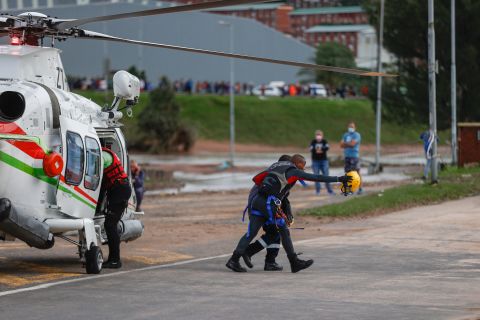 Спасатель идет с человеком, которому помогли с затопленного рабочего места недалеко от Умлази, Южная Африка, 12 апреля.
