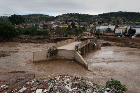 Река течет вокруг поврежденного моста 12 апреля после того, как сильный дождь разрушил его недалеко от Дурбана.
