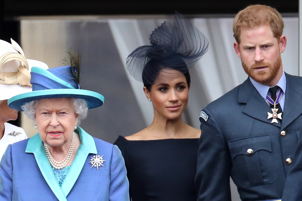 Королева Елизавета II, принц Гарри, герцог Сассекский и Меган, герцогиня Сассекская на балконе Букингемского дворца, когда члены королевской семьи посещают мероприятия, посвященные столетию Королевских ВВС, 10 июля 2018 года в Лондоне, Англия. 