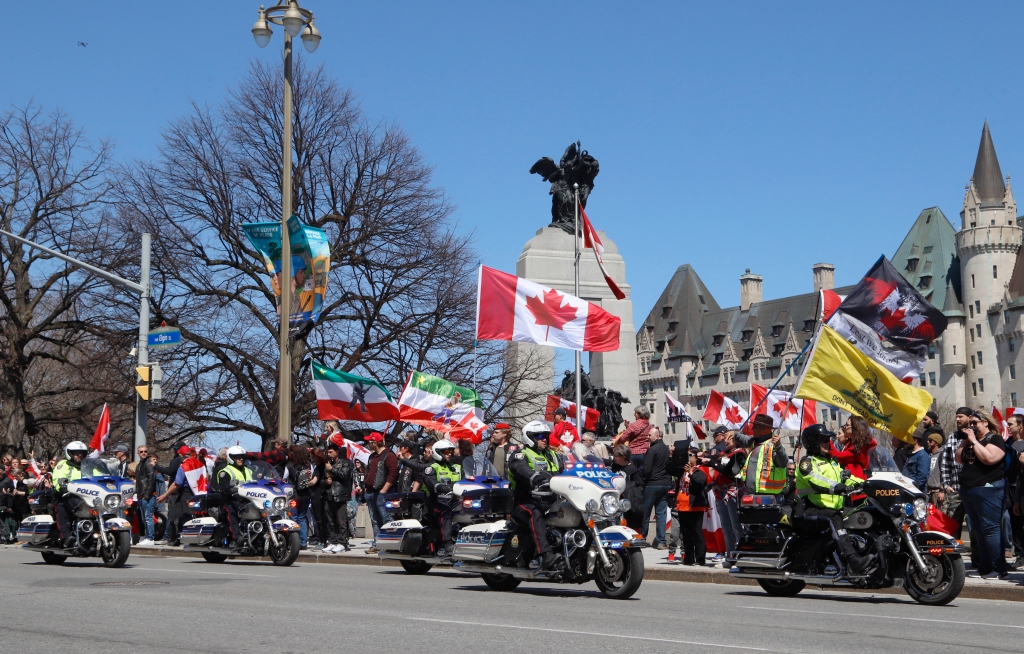 Полицейские на мотоциклах проезжают демонстрацию, участники демонстрации в стиле колонны призывают "раскаты грома" В Оттаве, Онтарио, в субботу, 30 апреля 2022 года.