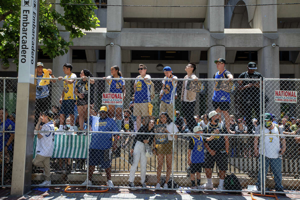Поклонники стоят на железнодорожных путях, наблюдая за действием во время парада чемпионата Golden State Warriors на Маркет-стрит в Сан-Франциско, Калифорния, 20 июня 2022 года.