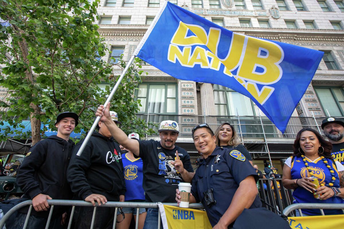 Фанат держит флаг Dub Nation во время обзора чемпионата Golden State Warriors Championship на Маркет-стрит в Сан-Франциско, Калифорния, 20 июня 2022 года.