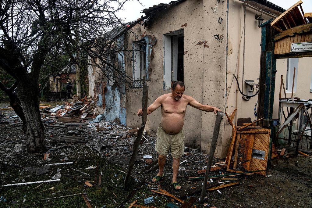 Местный житель расчищает завалы своего дома, который был разрушен после нападения российских войск на жилой район в центре Харькова.