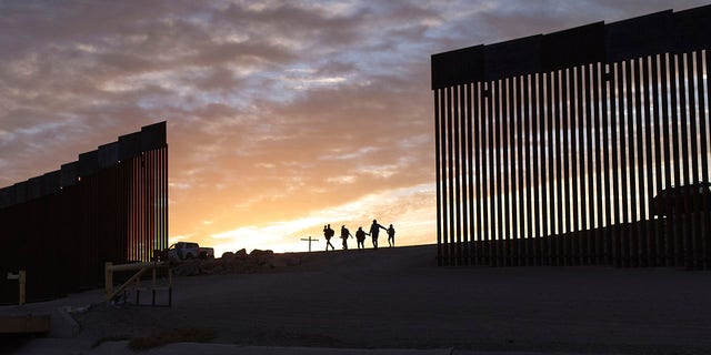 ФАЙЛ — Семьи иммигрантов из Бразилии проходят через брешь в пограничной стене, чтобы добраться до Соединенных Штатов после перехода из Мексики в Юму, штат Аризона, в поисках убежища.