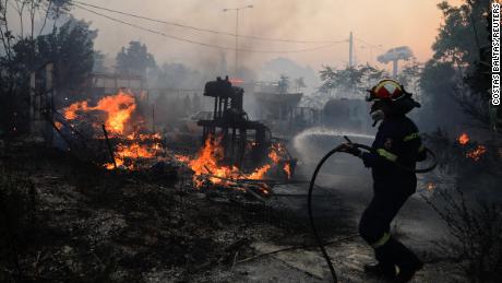Пожарный пытается потушить пожар в Палини, недалеко от Афин, Греция, 20 июля.