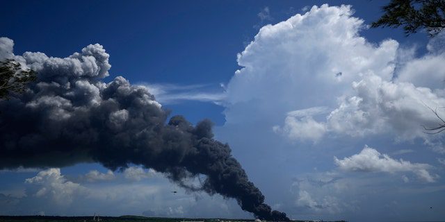 Огромный столб дыма поднимается над основанием супертанкера Матансас, когда пожарные тушат пожар, вспыхнувший во время грозы накануне вечером, в Матасанас, Куба, в субботу, 6 августа 2022 года.