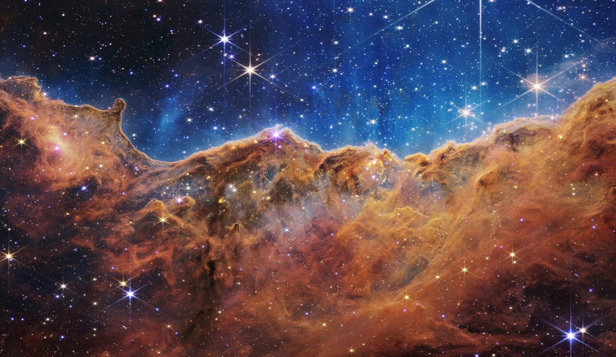 Туманность Киля: звезды мерцают на фоне цвета индиго над ржаво-бронзовыми газовыми облаками.